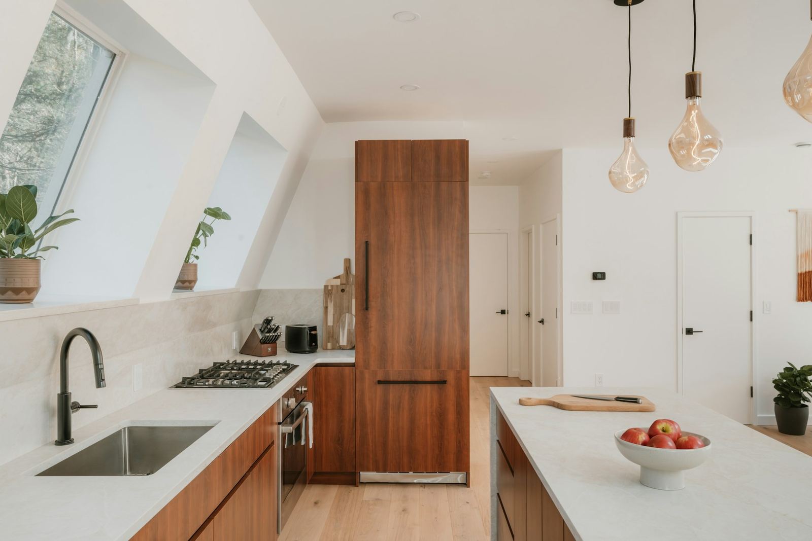 The Marblehead kitchen: walnut cabinetry, a long white island, skylights over the sink wall and light oak floors