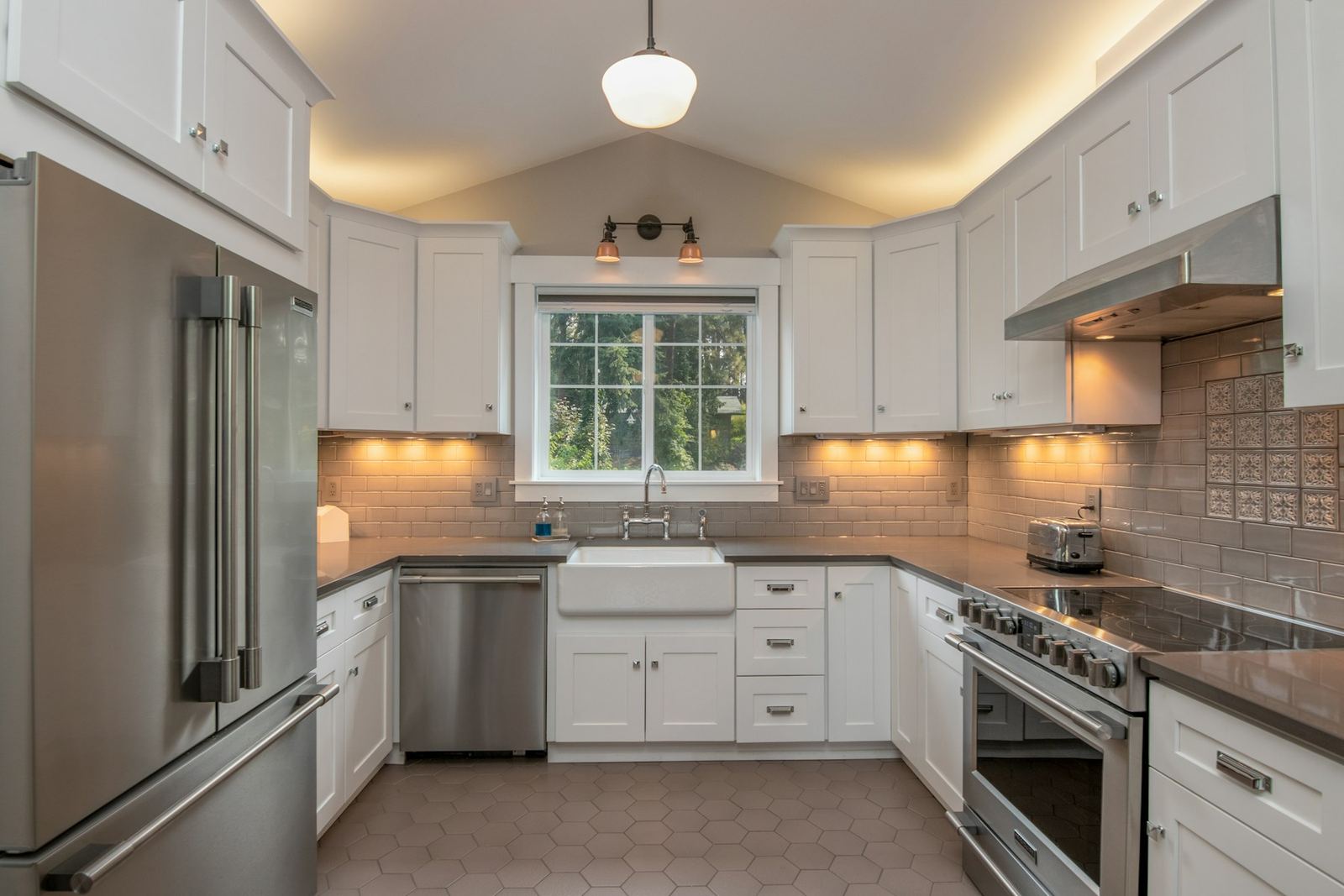 White shaker-style kitchen with a farmhouse sink and vaulted ceiling